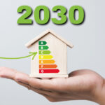 Hand holding a model house with EPC rating chart and 2030 energy efficiency target