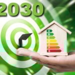 Hand holding energy efficiency house model with EPC rating chart and 2030 target in background