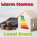 Model house with energy rating chart beside stacked coins, representing local grant for home energy efficiency.