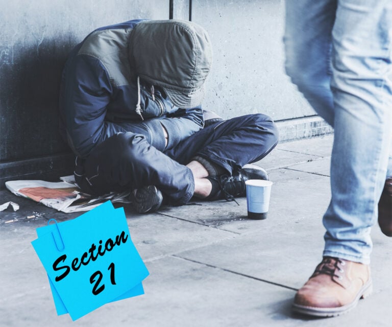 Person sitting on the street beside a cup as Section 21 eviction concept is highlighted