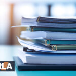 Stack of housing regulation documents and reports with NRLA logo