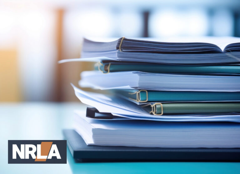 Stack of housing regulation documents and reports with NRLA logo