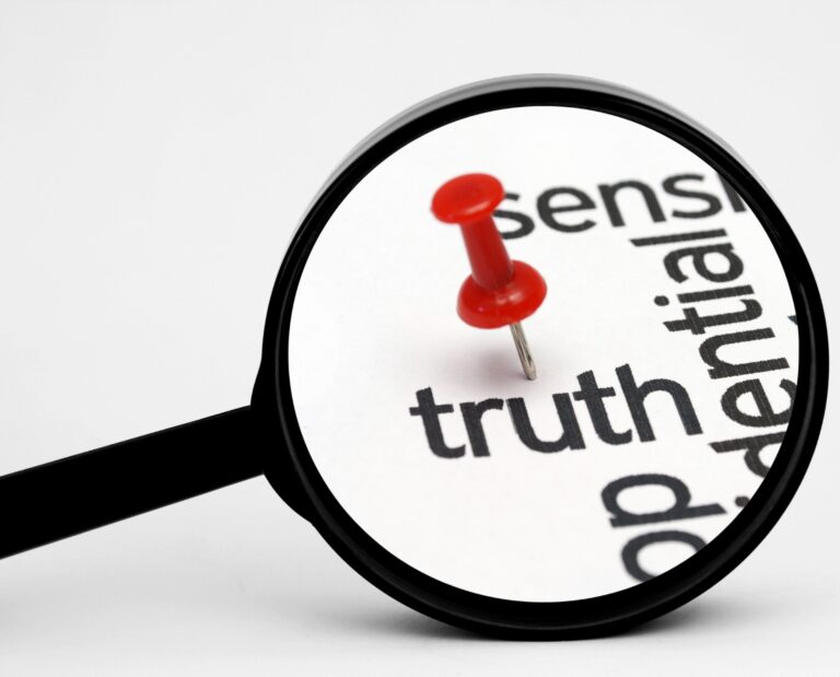 Magnifying glass highlighting the word “truth” with a red pushpin