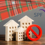 Wooden house models with red prohibition symbol representing rent control concerns in Scotland