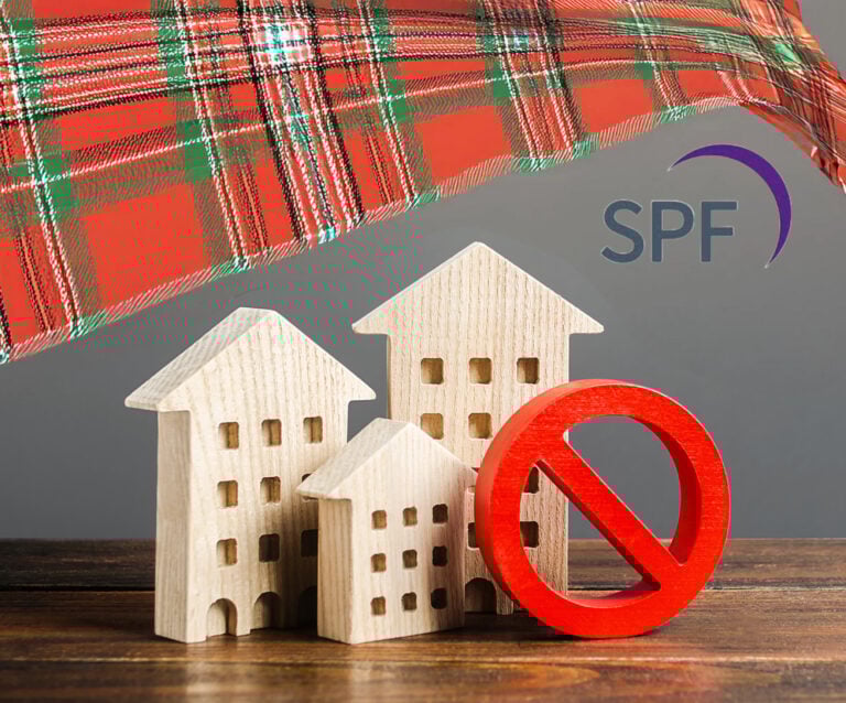 Wooden house models with red prohibition symbol representing rent control concerns in Scotland