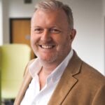 Business professional smiling in office setting, representing landlord support discussion ahead of the Budget