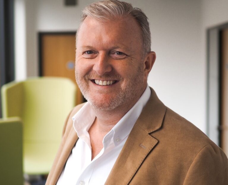 Business professional smiling in office setting, representing landlord support discussion ahead of the Budget