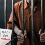 Tenant in prison behind bars with rent arrears note highlighting unpaid rent issue