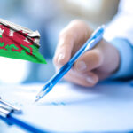 Welsh flag beside person signing housing policy document