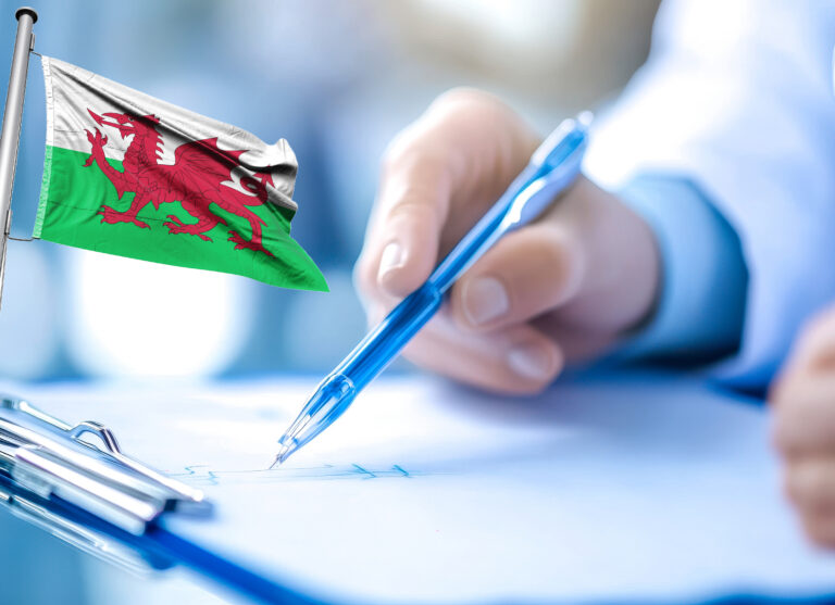 Welsh flag beside person signing housing policy document