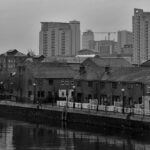 Salford riverside homes with modern high-rises in the background on an overcast day.