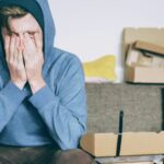 Stressed renter sitting with hands over face, reflecting anxiety over housing insecurity
