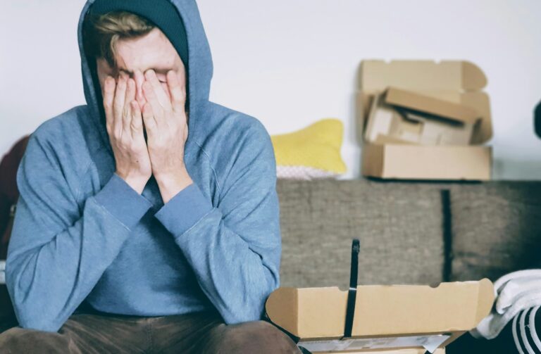 Stressed renter sitting with hands over face, reflecting anxiety over housing insecurity