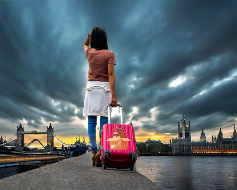 Traveller with suitcase overlooking Tower Bridge and London skyline at sunset