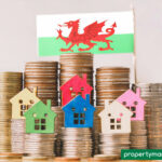 Stacks of coins with colourful house icons and Welsh flag symbolising rising housing costs in Wales