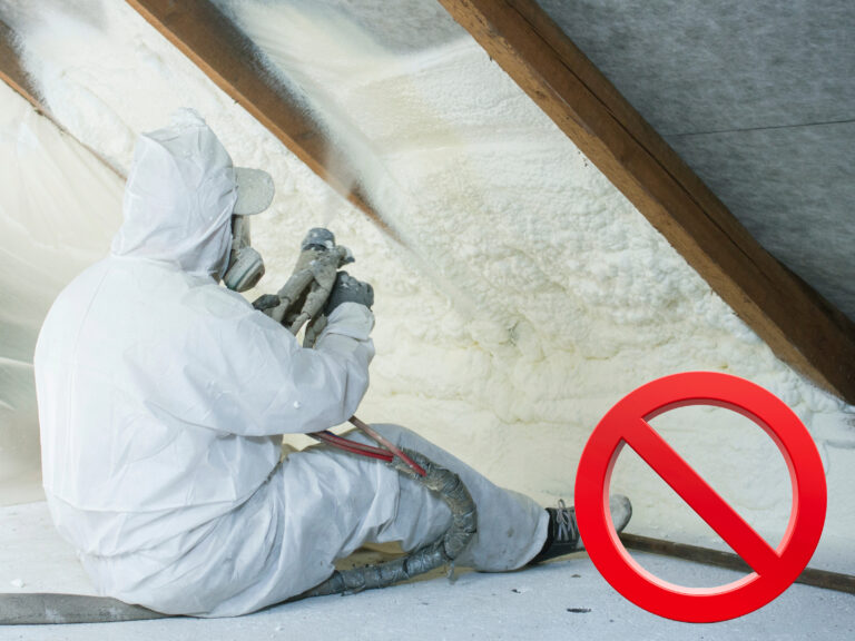 Worker spraying foam insulation in attic with red prohibition symbol