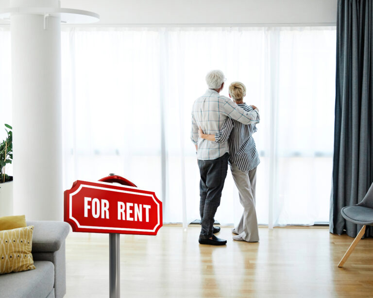 Older couple viewing rental apartment with “For Rent” sign, reflecting retirement housing challenges