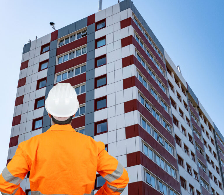 Construction inspector assessing cladding on a high-rise residential building