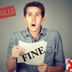 Shocked landlord holding fine notice with "FAILED" stamp and house crossed out.