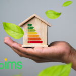 Hand holding a wooden house with EPC energy rating chart and green leaves symbolizing efficiency