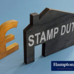Wooden house shape with "Stamp Duty" beside a gold pound sign symbolising property tax costs.