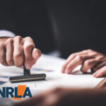 Hand stamping approval on landlord licensing documents with NRLA logo