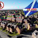 Aerial view of suburban housing estate with Scottish flag showing 28,000 empty homes crisis.