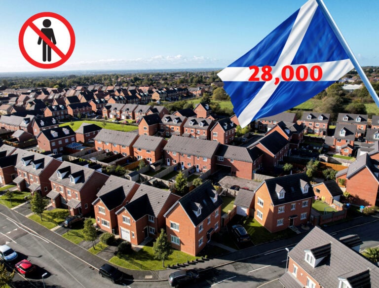 Aerial view of suburban housing estate with Scottish flag showing 28,000 empty homes crisis.