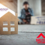 Cardboard house model with blurred homeless person in background, highlighting housing crisis in Edinburgh