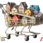 Shopping cart filled with model houses symbolising growing property portfolios.