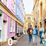 Students walking through a colorful street near a university campus highlighting rising rent costs.