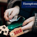 Person handling money with sold house tag symbolizing property sale profits