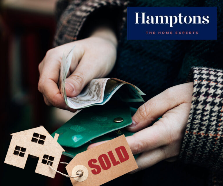 Person handling money with sold house tag symbolizing property sale profits