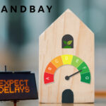 Wooden house model with EPC rating gauge and delay warning sign.