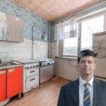 Run-down council kitchen with outdated appliances and housing law expert in foreground
