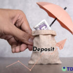 Hand placing money in a deposit bag under an umbrella symbolising deposit protection