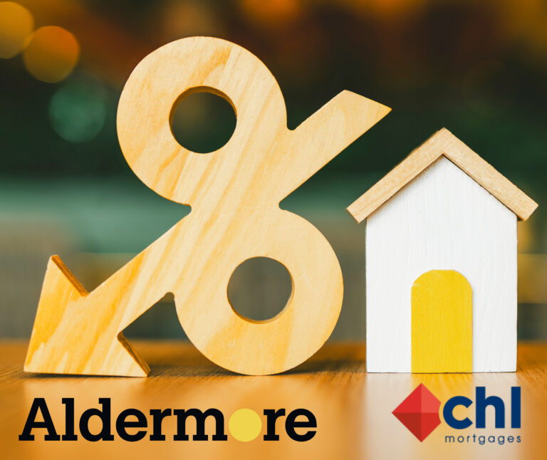 Wooden percentage sign with arrow beside small house model representing mortgage rate cuts.