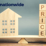 Wooden house model balanced against price blocks representing UK housing market trends