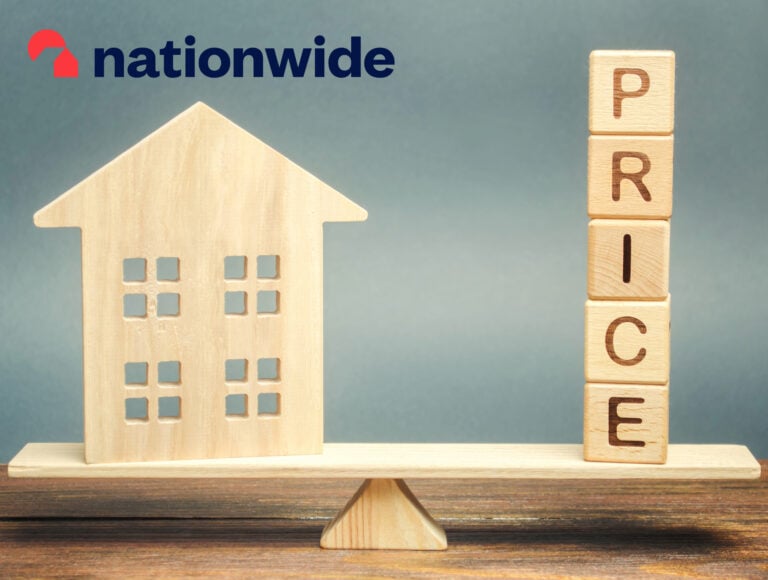 Wooden house model balanced against price blocks representing UK housing market trends