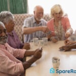 Group of older adults socialising and playing cards together, symbolising the rise of older tenants in UK flatsharing