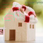 Wooden house model with life ring and for rent sign symbolising landlord support in rental market.