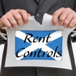 Businessman tearing paper with Scottish flag and words “Rent Controls”