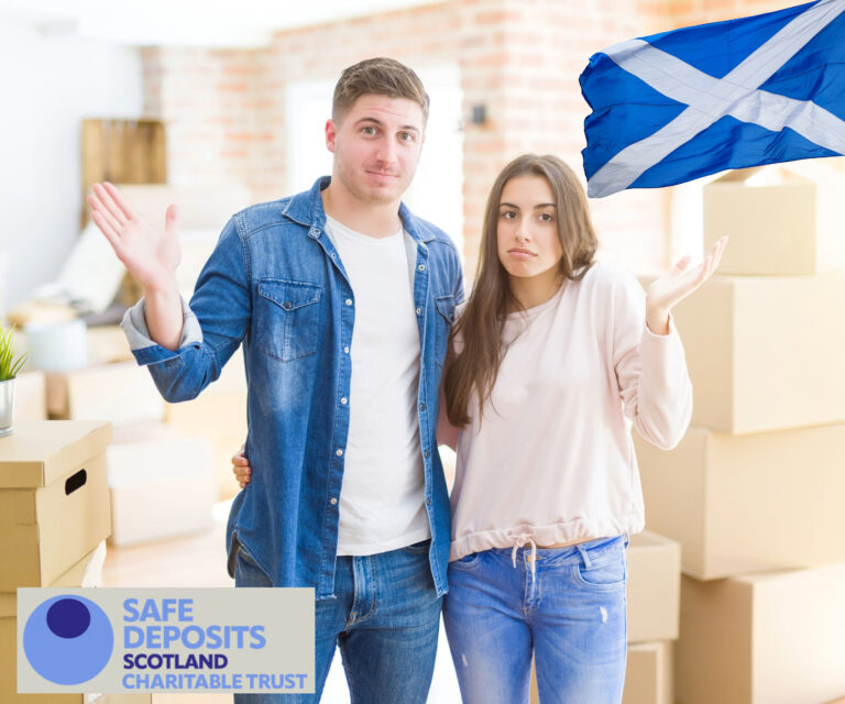 Confused couple with moving boxes and Scottish flag, highlighting tenant issues in Scotland’s rental sector