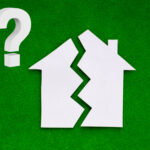 Paper house split in two with a question mark on green background