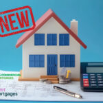 A model home on a desk, a calculator, a pen and paperwork
