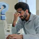 A man sitting at a laptop and a question mark