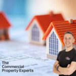 Smiling commercial property expert in front of model houses with The Commercial Property Experts logo