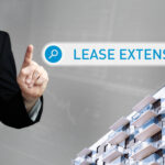 Person pointing at lease extension search with modern apartment building.