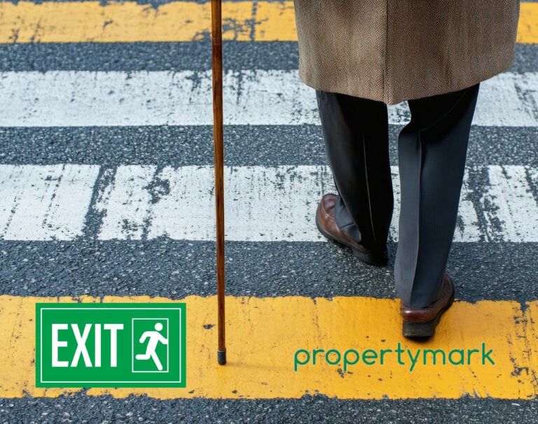 An elderly person crossing the road with a stick. Exit