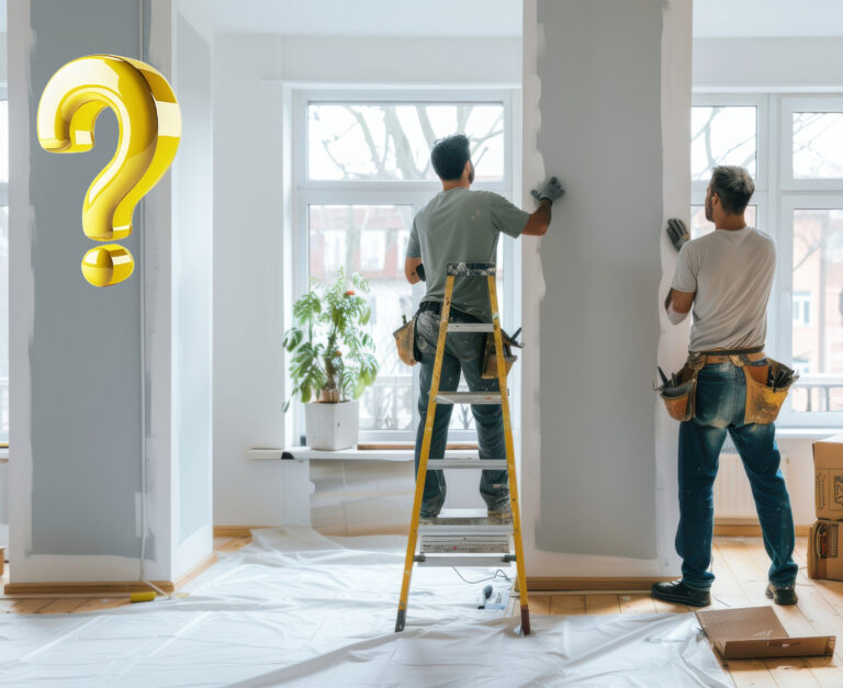 Two workers repainting an empty flat with a large golden question mark added.